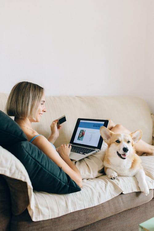 A Woman Sitting on Couch with her Dog Shopping Online
