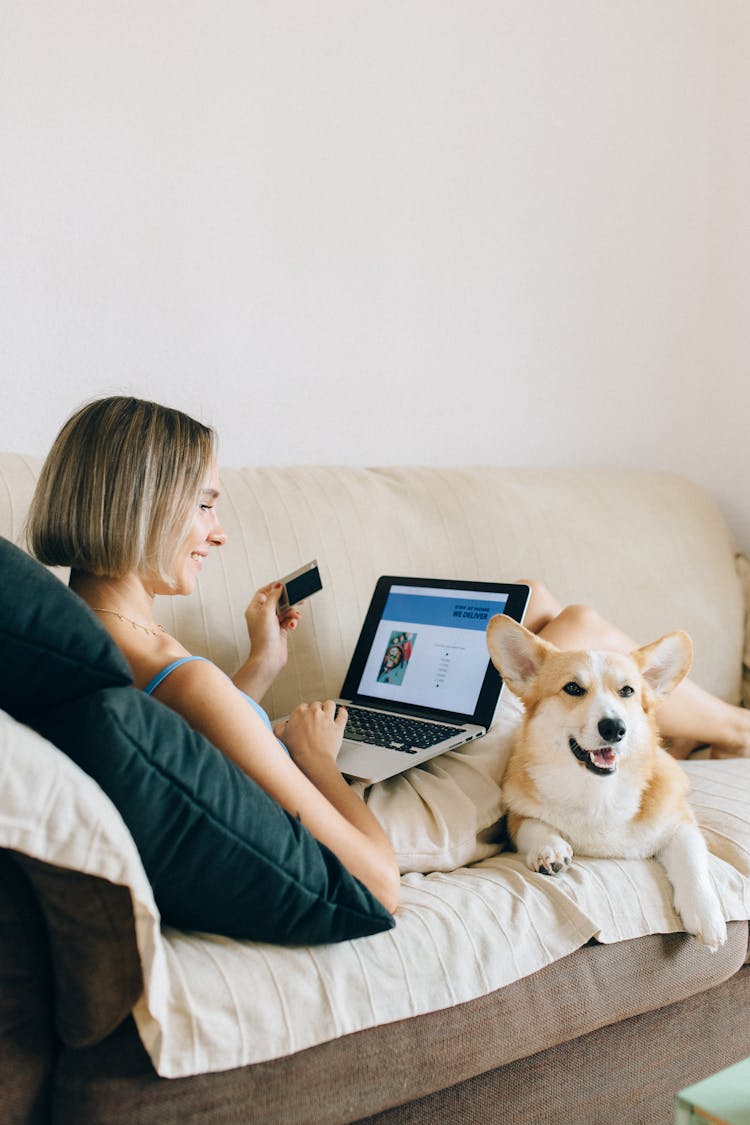 A Woman Sitting On Couch With Her Dog Shopping Online