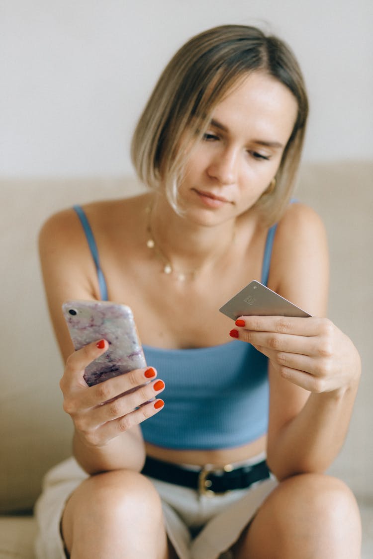 A Woman Holding Her Phone And Credit Card