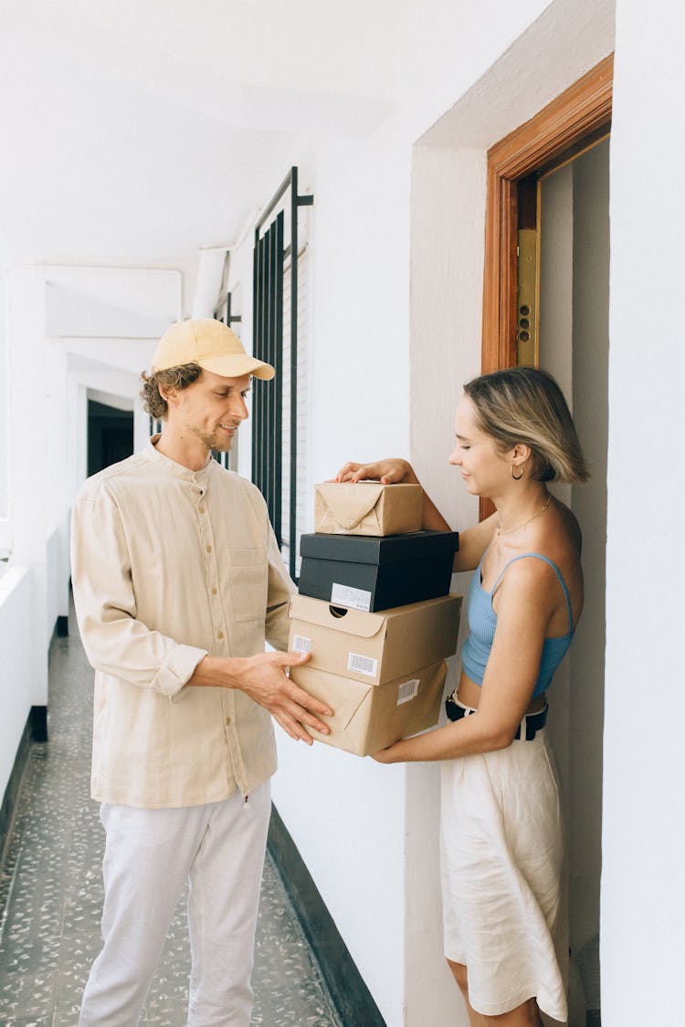 Woman In Blue Spaghetti Strap Top Receiving A Packages From A Delivery Man