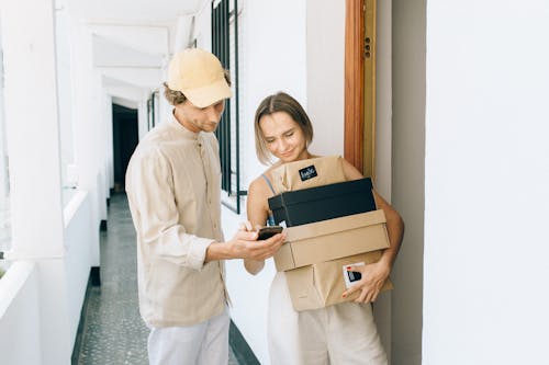 A Woman Receiving Her Parcels while Standing Beside the Delivery Man