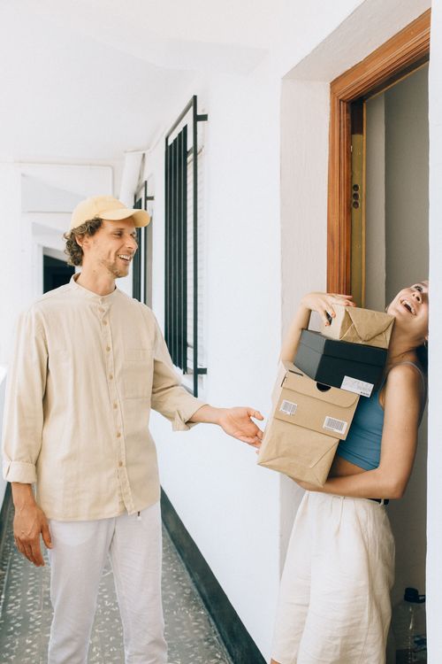 Free A cheerful couple receives delivery boxes at their home doorway, illustrating joy and convenience. Stock Photo