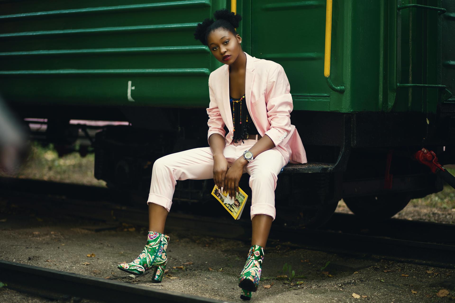 Stylish woman in pink suit posing by a train in a Ukrainian district.