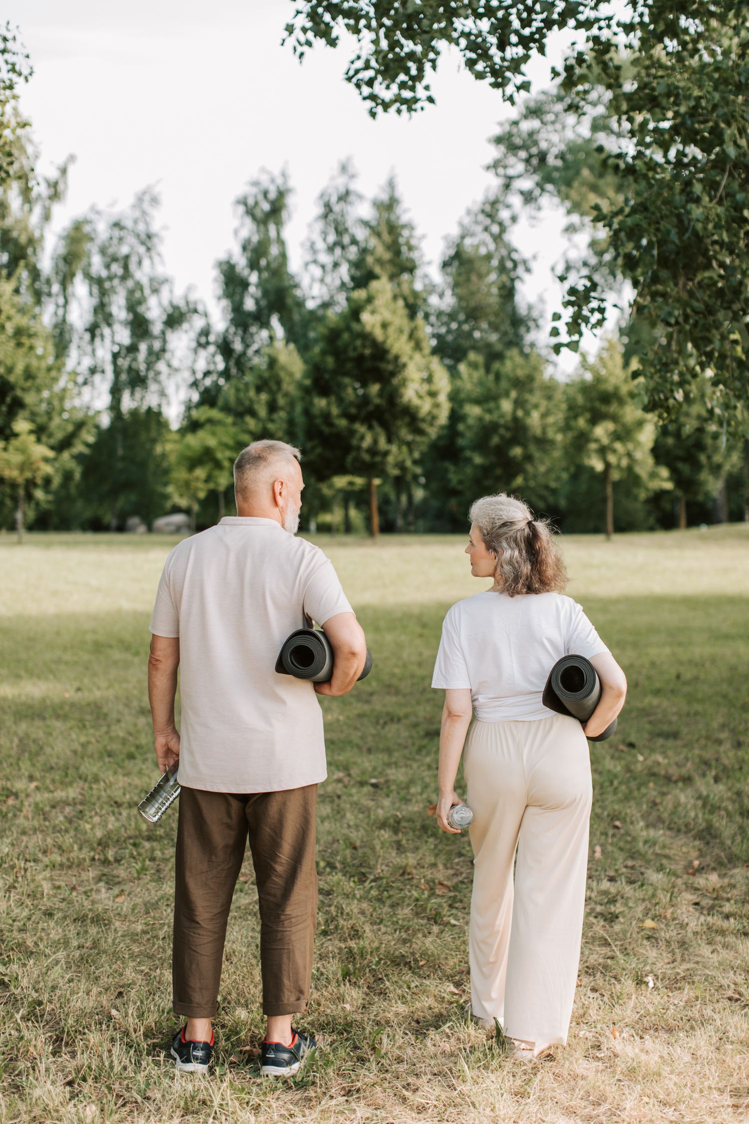Un couple âgé se promène dans un parc avec des tapis d'exercice