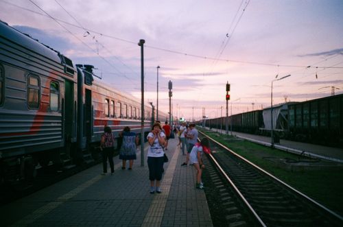 Free Commuters on a railway platform with a train at sunset, capturing the daily travel routine. Stock Photo