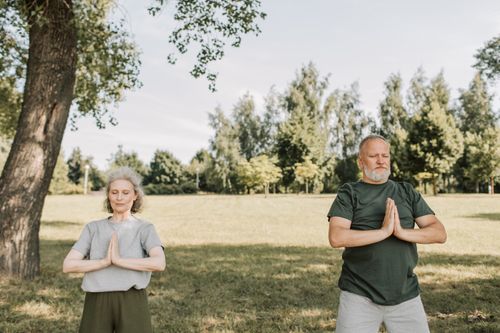 Free Elderly couple meditating in a calm park setting, embracing fitness and tranquility outdoors. Stock Photo