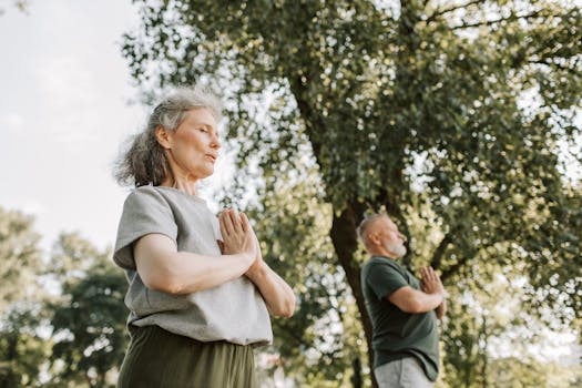 Senior couple meditating outdoors in nature during the day, promoting health.