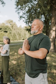 Elderly couple practicing yoga and meditation outdoors for wellness and relaxation.