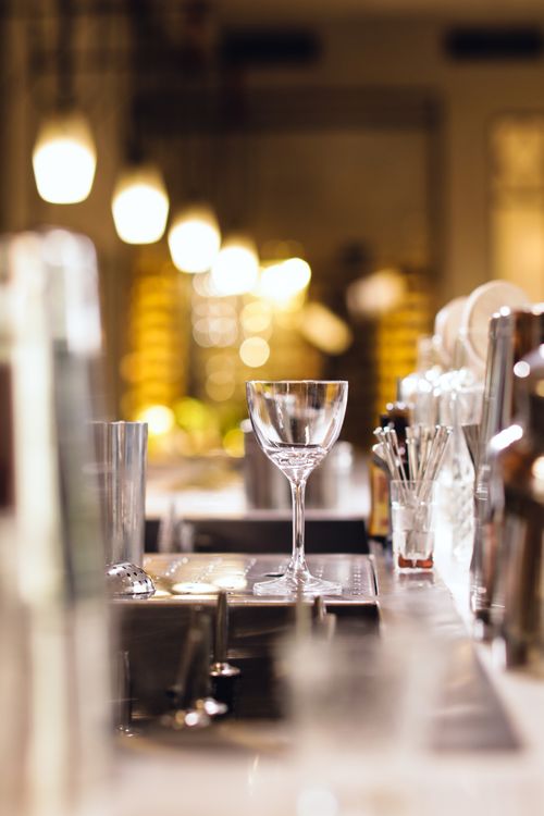 Free Close-up of an empty glass in a stylish bar setting with warm lighting and bokeh effect. Stock Photo