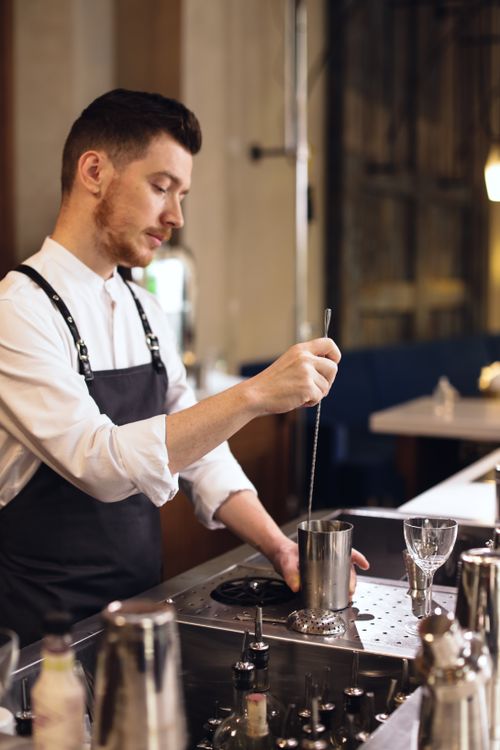 Free A focused bartender mixes a cocktail at an upscale bar, demonstrating skilled bartending techniques. Stock Photo