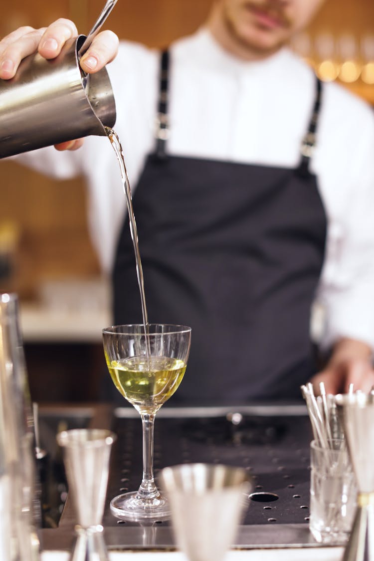 A Bartender Pouring A Drink Into A Glass