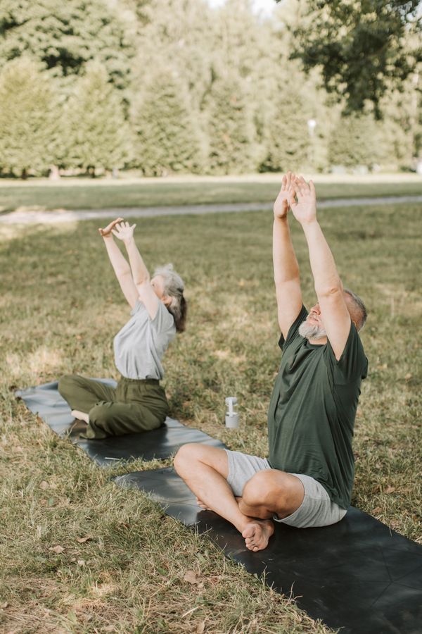 Couple practising yoga together outdoors