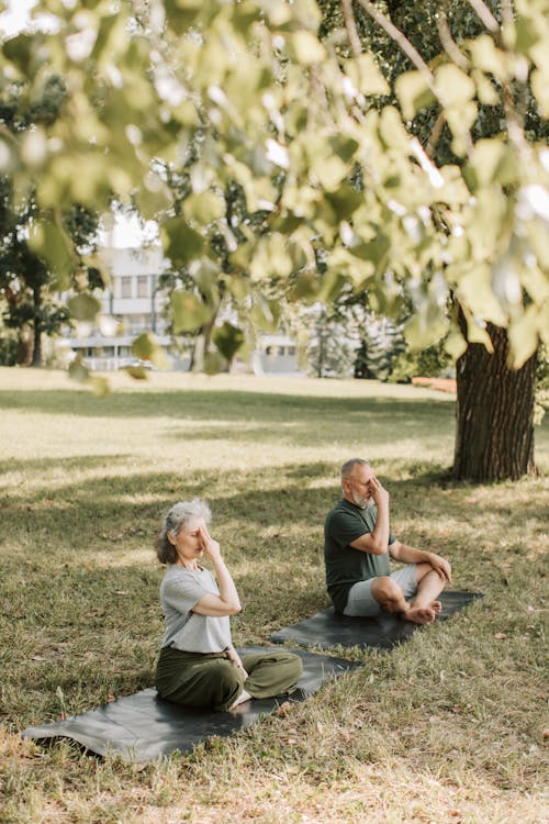 An Elderly Couple Sitting on Yoga Mat while Meditating