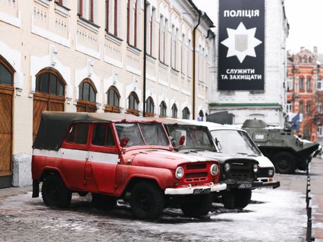 Red and white vintage cars parked in front of a historic building with a police sign.