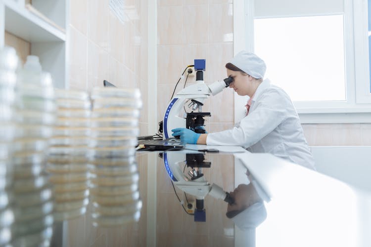 A Side View Of A Woman Looking At The Microscope