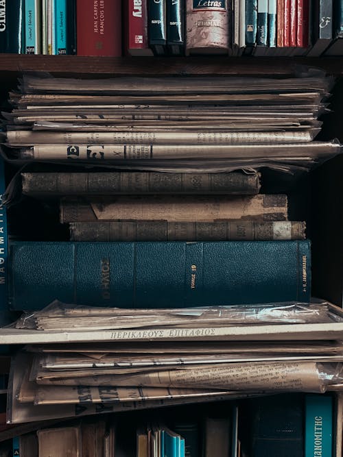 Free Collection of Books and Newspapers on a Bookshelf Stock Photo
