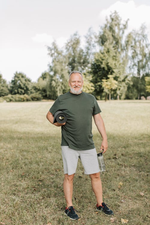 A Man Holding Yoga Mat and a Water Bottle