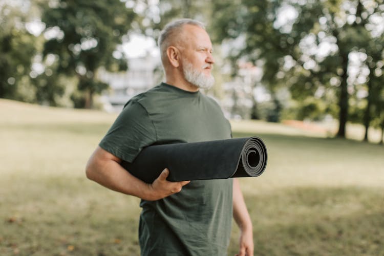 An Elderly Man Holding A Yoga Mat 