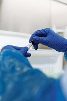 Scientist in blue gloves handling a sample tube in a laboratory setting.