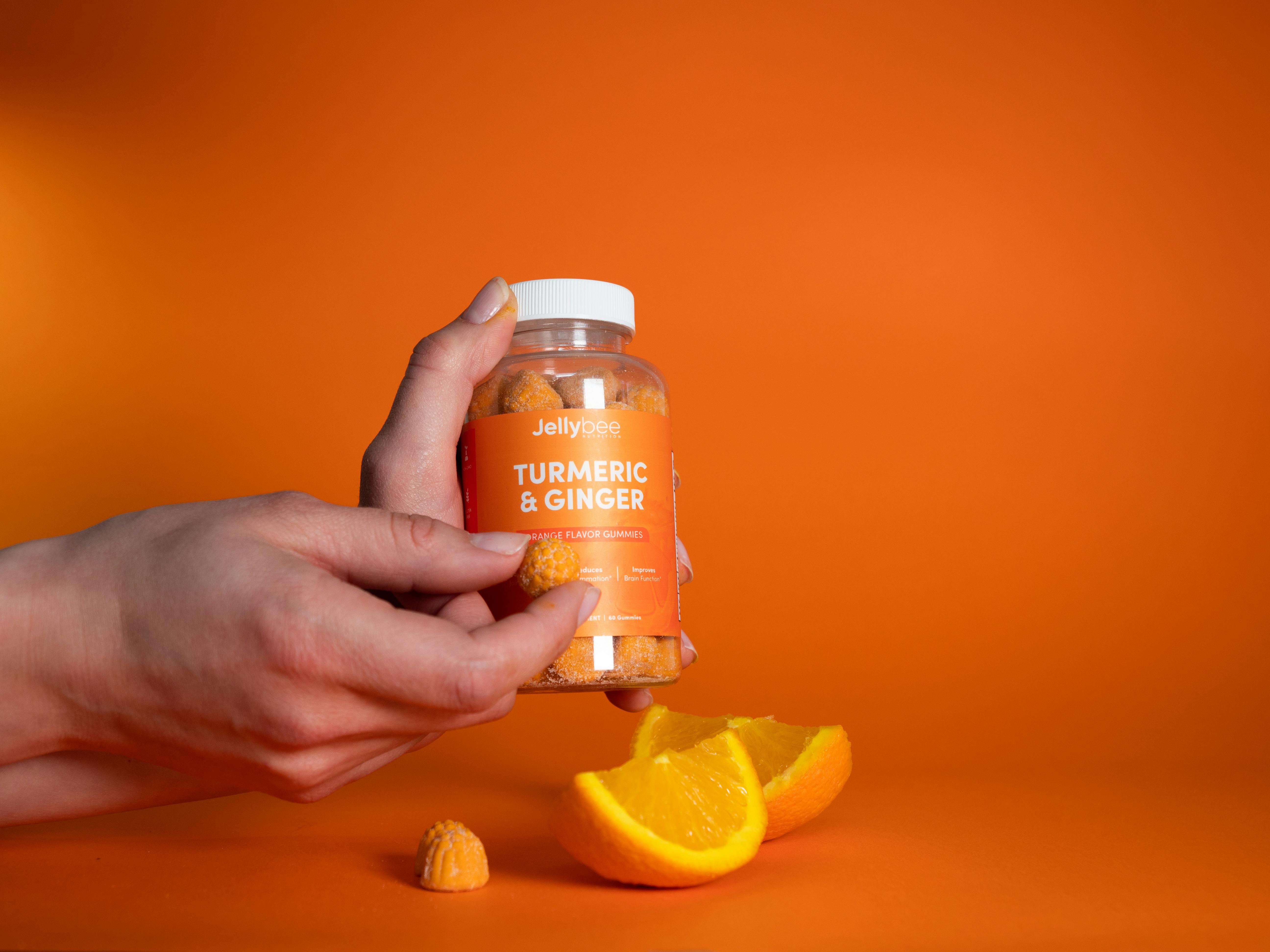 person holding a gummy from an orange plastic bottle