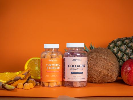 Colorful tropical gummies with fresh fruits including coconut, pineapple, and orange.