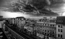 布加勒斯特的城市景观呈现黑白色调，上空笼罩着巨大的风暴云