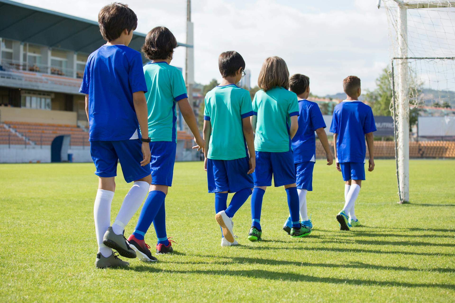 Children Wearing Jerseys Walking on a Football Field