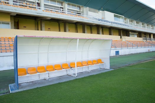 Empty team bench at a football stadium in Portugal, showcasing vibrant seats and lush grass.