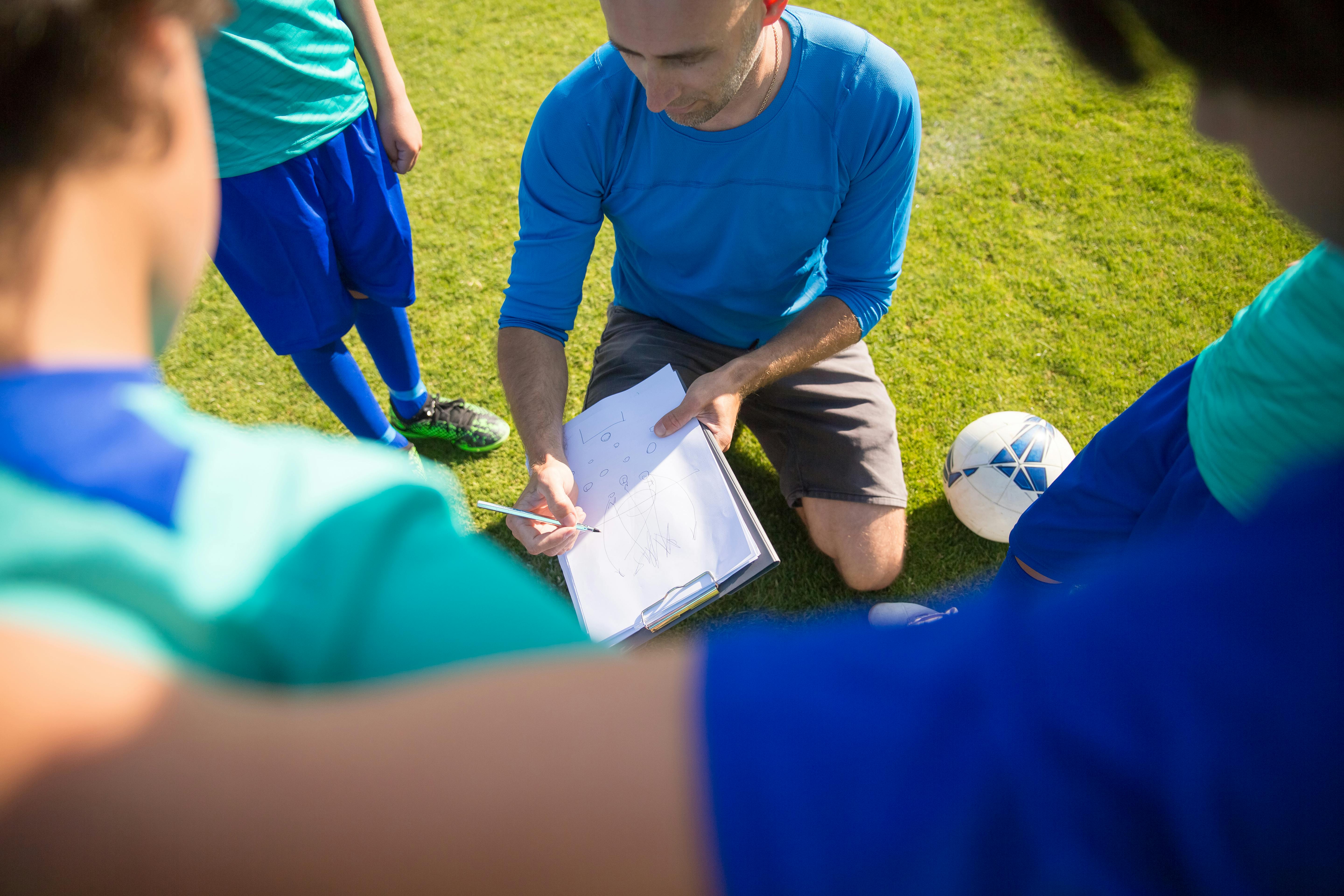 man in blue crew neck shirt coaching a group of kids