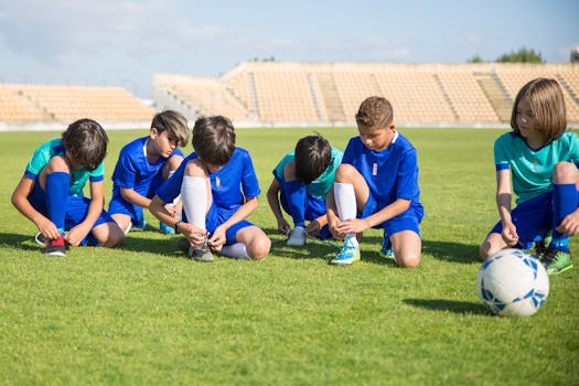 Group of young soccer players putting on shoes in a stadium in Portugal.