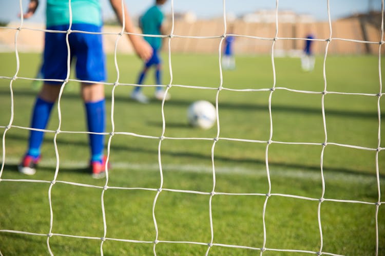 A Net With People Playing Soccer On The Background