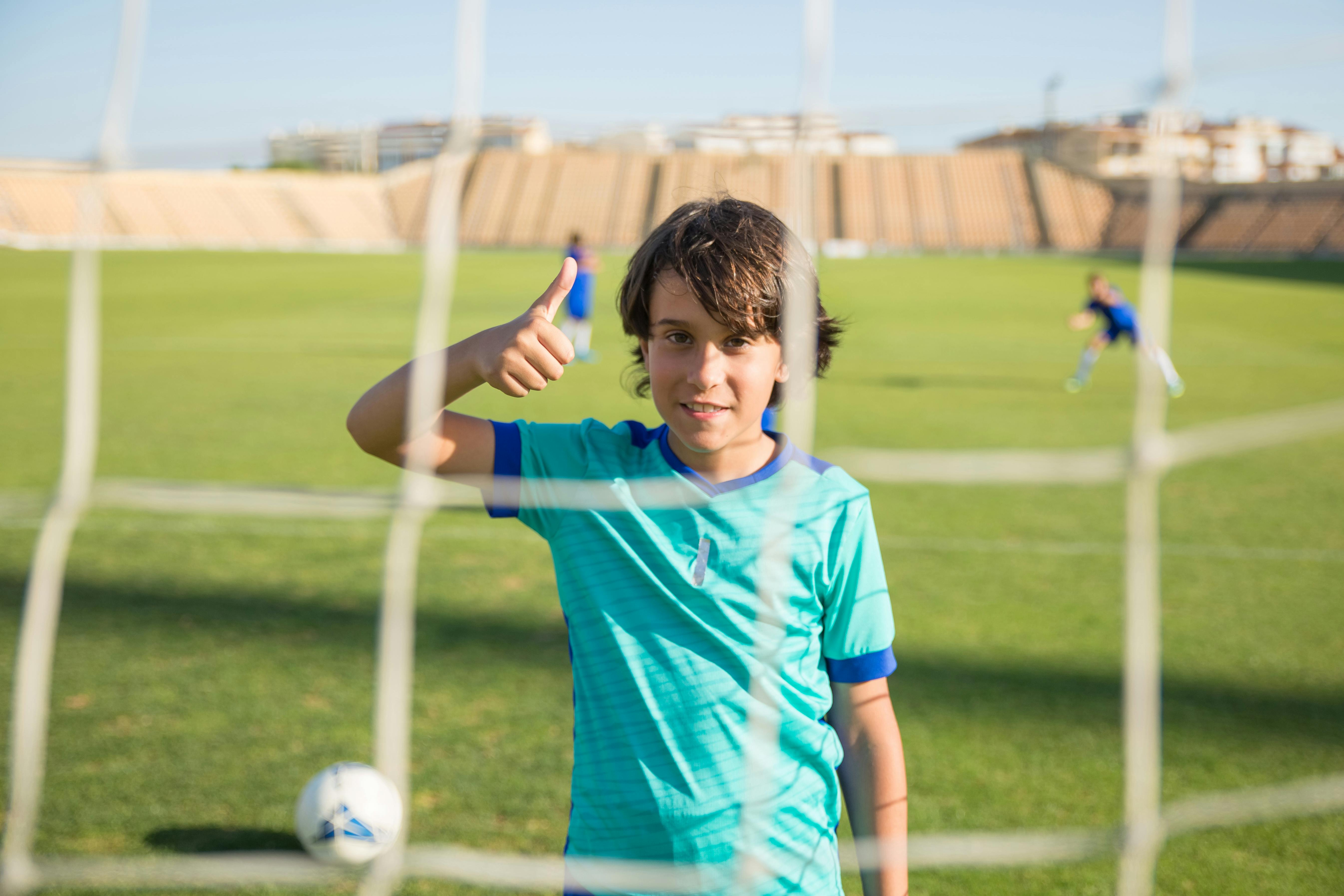 a young boy doing thumbs up sign while on the field