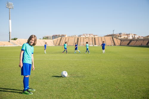 Boy in Blue Jersey Standing on a Football Field