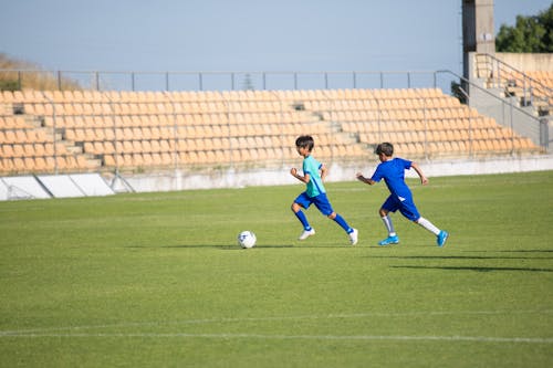 Young Boys Running while Playing Football