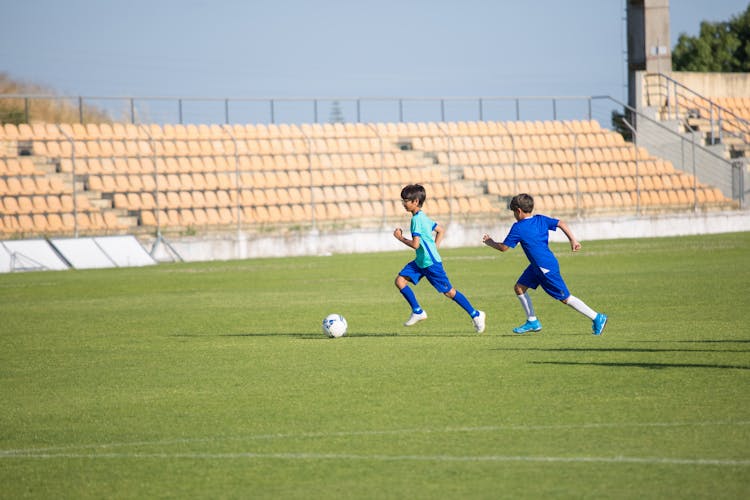 Young Boys Running While Playing Football