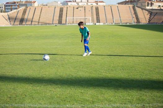 A boy trains on an outdoor soccer field in a stadium on a sunny day in Portugal.
