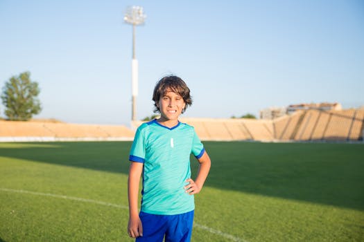 Boy in soccer uniform posing confidently on a sunny field in Portugal.