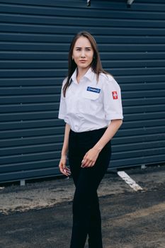 Portrait of a professional paramedic woman standing outdoors in uniform, conveying readiness and professionalism.