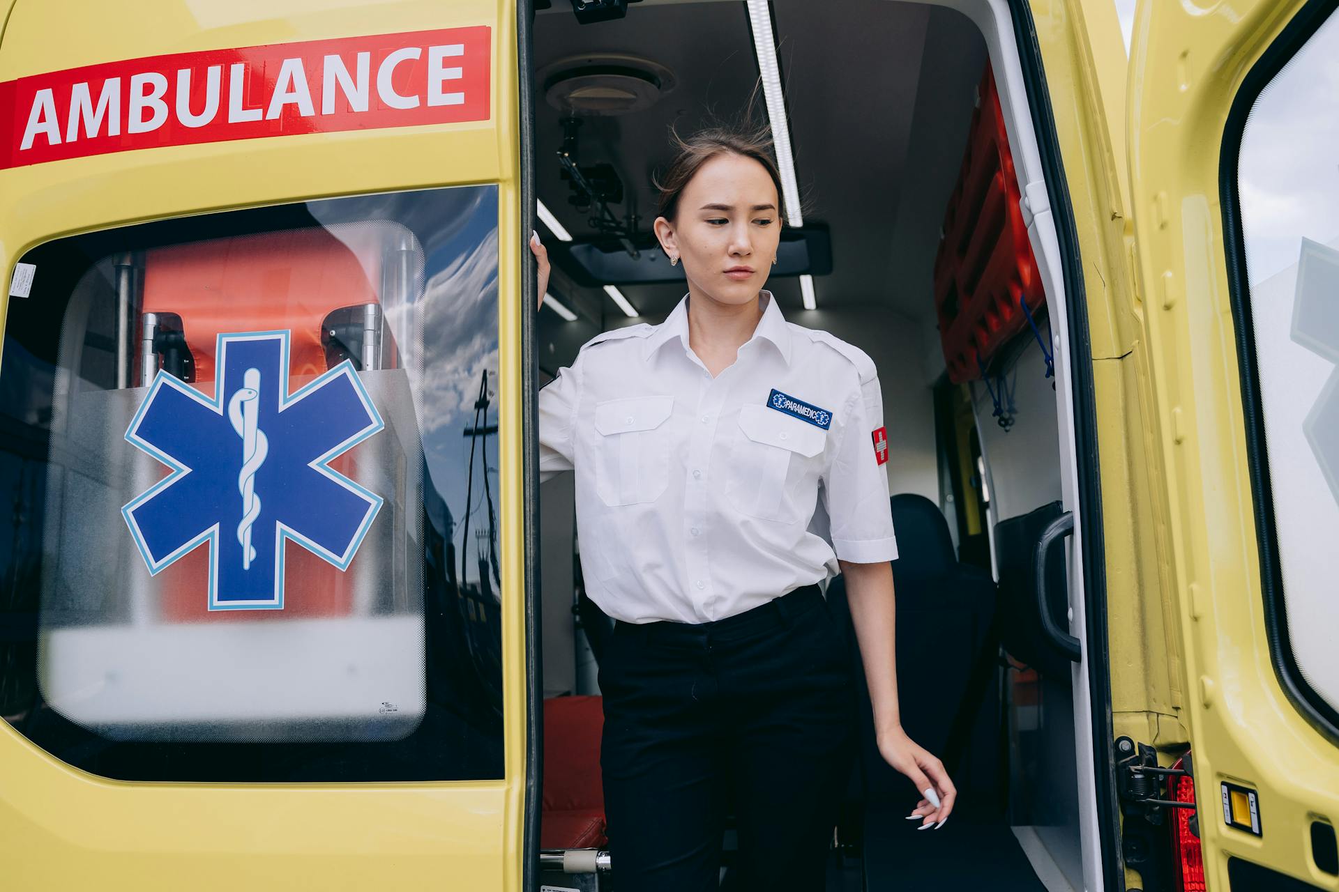 Woman in EMT Uniform Standing on an Ambulance