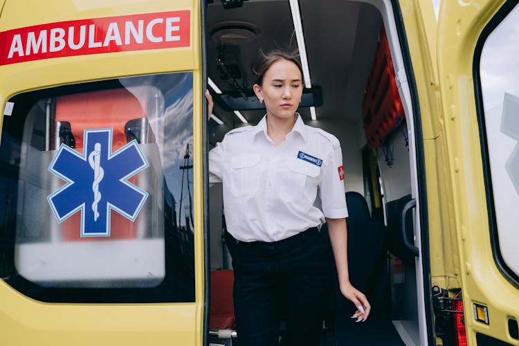 Woman In EMT Uniform Standing On An Ambulance