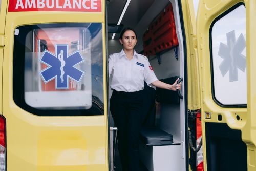 Free A paramedic in uniform stands at the rear of an ambulance, ready for action. Stock Photo
