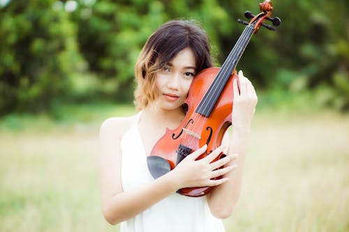 Woman in White Tank Top Holding a Violin
