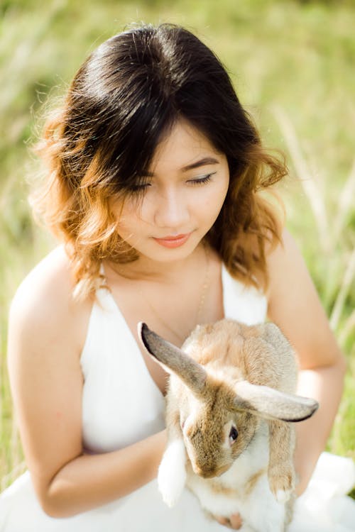 A Woman in White Tank Top Holding a Rabbit