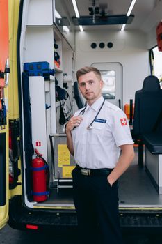 Professional medic standing by an open ambulance, ready for emergency response.