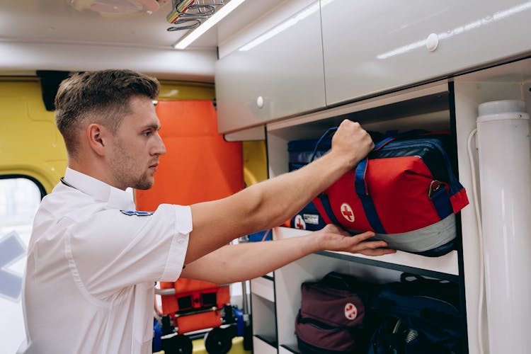 A Paramedic Grabbing A First Aid Bag Inside An Ambulance