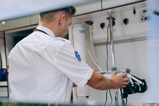Paramedic adjusting medical equipment inside an ambulance, representing emergency healthcare services.