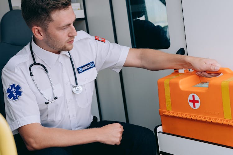 A Man Sitting While Holding A First Aid Kit