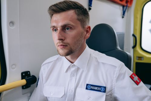 Free Paramedic in uniform seated inside an ambulance, ready for emergency medical service. Stock Photo