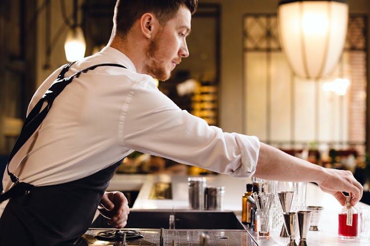 Side View Of A Bartender Making A Drink At A Bar