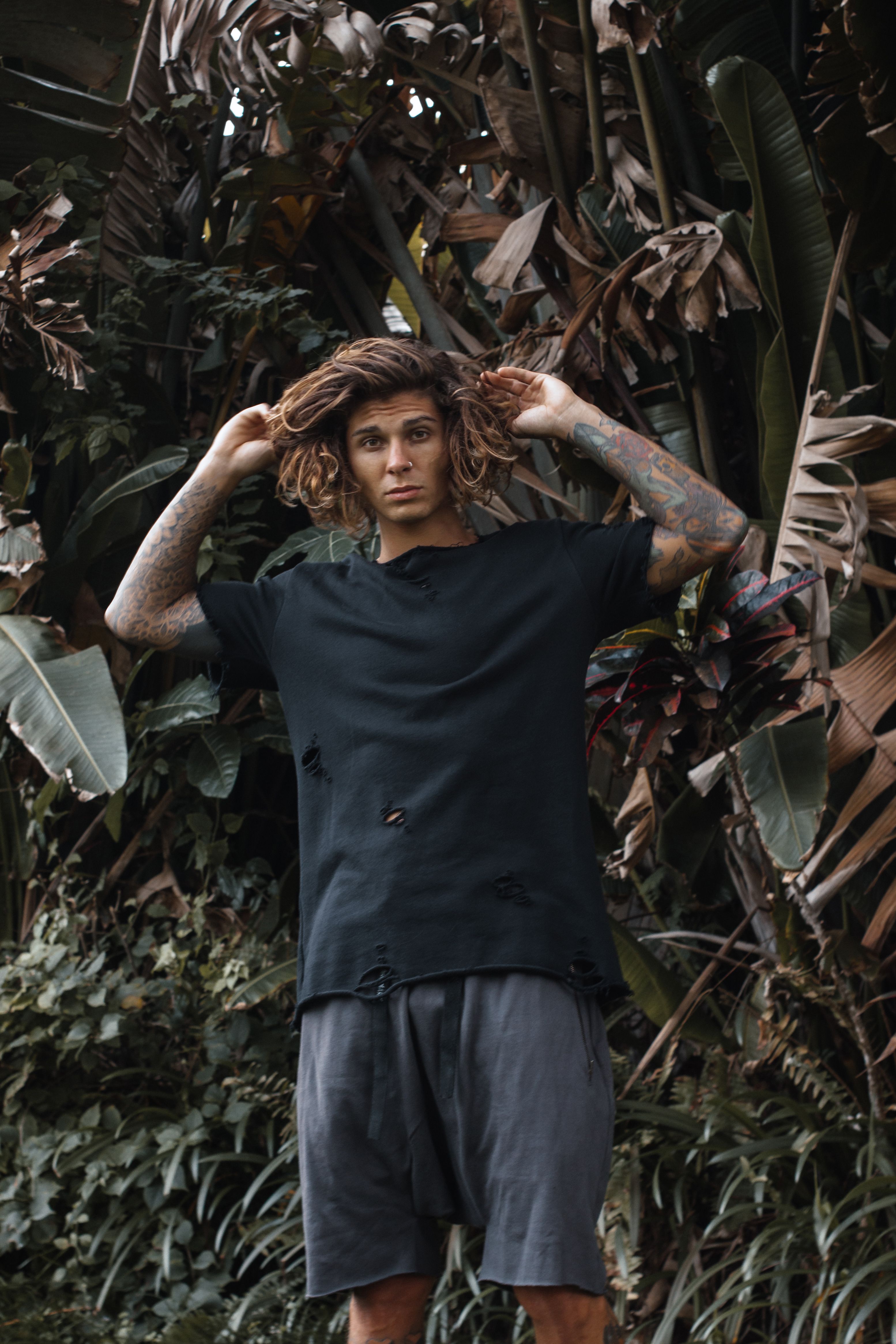 Man Wearing Ripped Clothes Standing Beside the Plants · Free Stock Photo